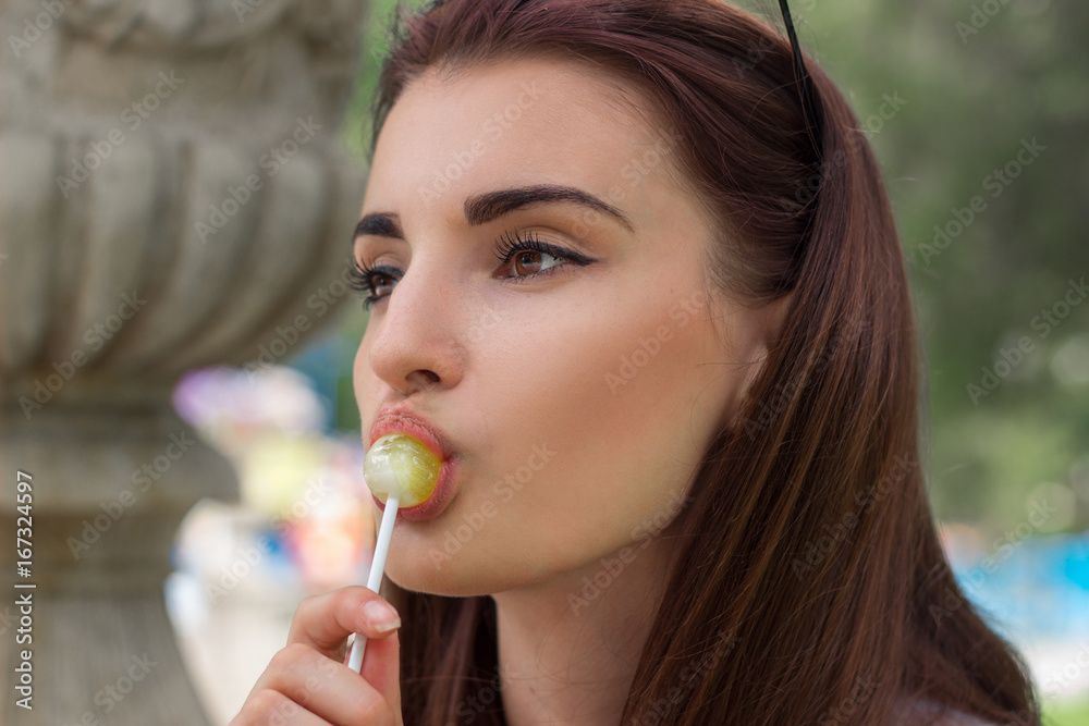 close up portrait of beautiful brunette girl licks a lollipop