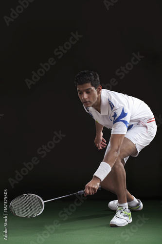 Young man in sportswear playing badminton over black background © IndiaPix