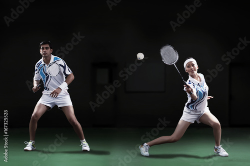 Man and woman playing badminton doubles at court