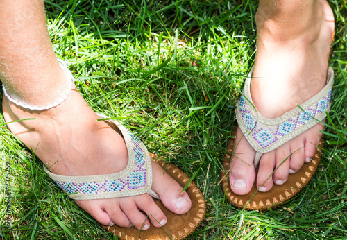 Young Girl's Feet in Sandals on Grass