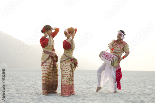 Bihu women dancing as Bihu man plays on a dhol  photo