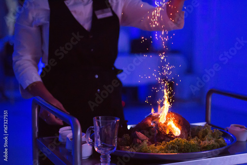 Chef, pouring alcohol into a frying pan with fire