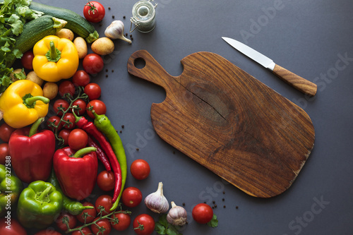 top view of fresh ripe vegetables with cutting board and knife on grey
