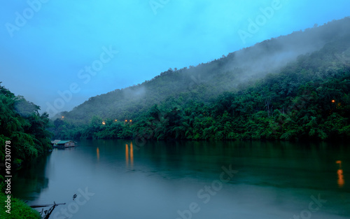 Fototapeta Naklejka Na Ścianę i Meble -  Mountain forest with fog and houseboat on kwai river landscape on rain in kanchanaburi, Thailand. Natural concept