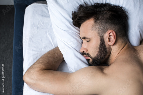 close-up view of handsome young bearded man sleeping in bed at home