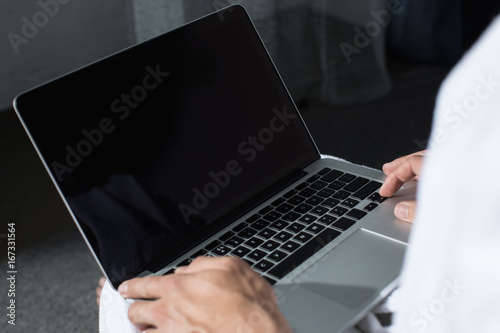 cropped shot of man using laptop with blank screen