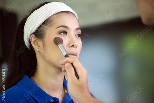 Fototapeta Naklejka Na Ścianę i Meble -  Beautiful Asian woman makeup by artist holding makeup brush.