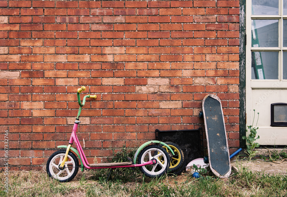 Bicicletta e skateboard poggiati su muro di laterizi