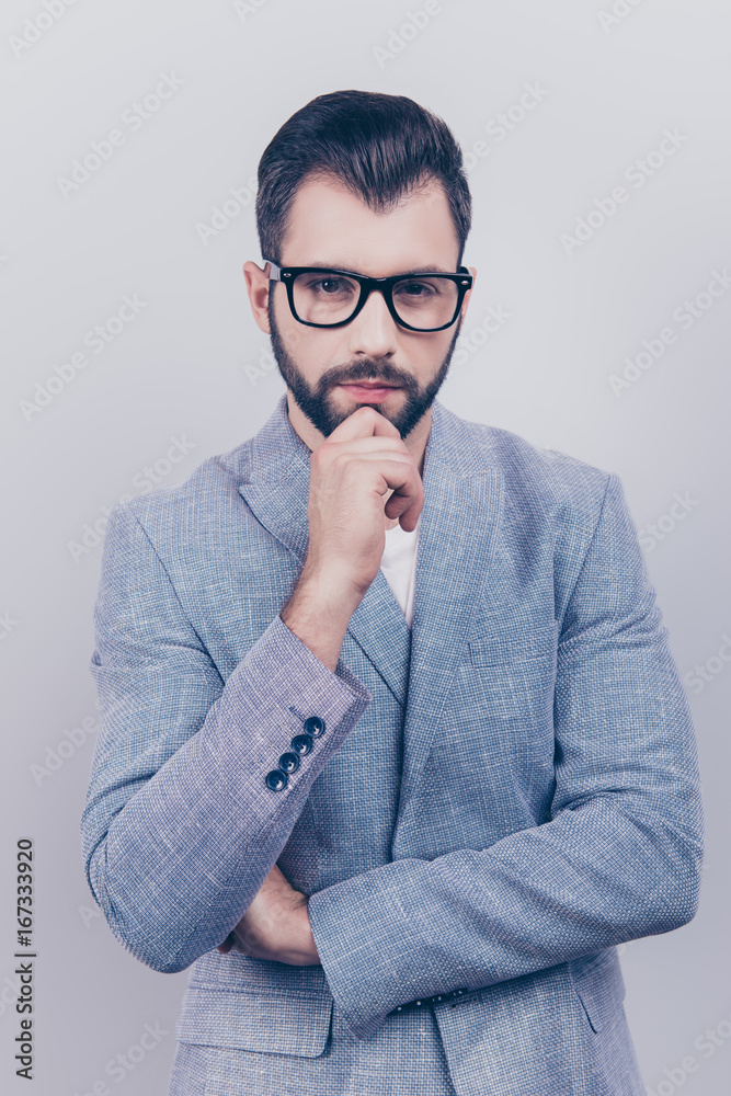 Successful young brutal bearded brunet banker in formal wear and black trendy glasses is standing isolated on a pure background and looks at the camera Successful young brutal bearded brunet banker in formal wear and black trendy glasses is standing isolated on a pure background and looks at the camera
