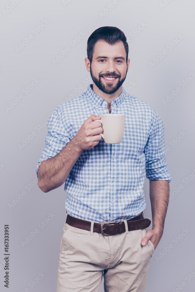 Young dreaming brunet bearded worker in formal wear is standing with the mug of tea isolated on pure background. He is relaxed, happy, smiling Young dreaming brunet bearded worker in formal wear is standing with the mug of tea isolated on pure background. He is relaxed, happy, smiling