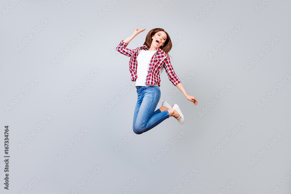 Funky, happiness, dream, fun, joy concept. Very excited happy cute teen student is jumping up, showing v sign, on light grey background
