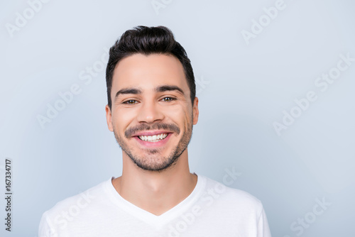 Health, beauty and dental concept. Excited young stylish bearded brunet student in white casual t shirt standing on light background