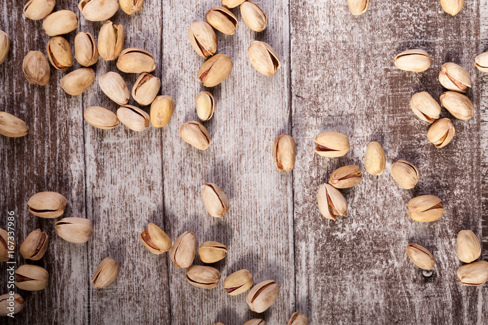 Spread Pistachios on wooden background in studio photo. Healthy delicious snacks