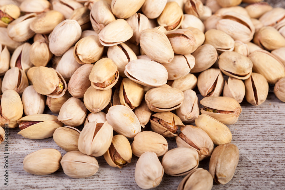 Over top close up view of Pistachios on wooden background in studio photo. Healthy delicious snacks Over top close up view of Pistachios on wooden background in studio photo. Healthy delicious snacks