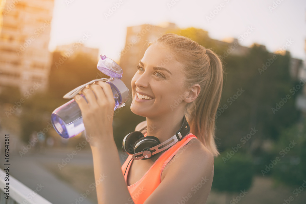 Beautiful sporty woman drinking water while resting from exercise. Beautiful sporty woman drinking water while resting from exercise.