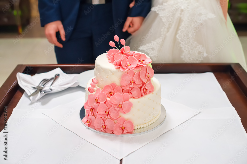 Bride and groom cutting their wedding cake decorated with orchids. Bride and groom cutting their wedding cake decorated with orchids.