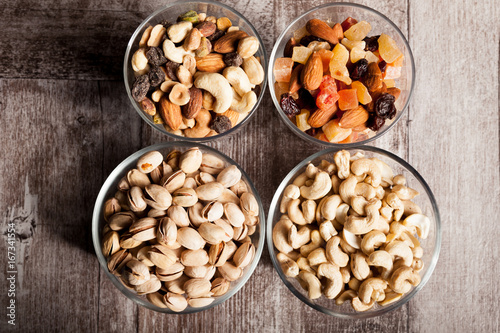 Healthy mix of dried nuts and sweets in was glass on wooden background in studio photo