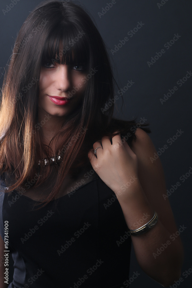 Belle femme brune posant devant un fond gris 