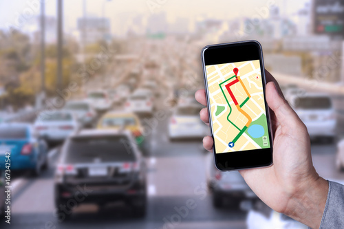 Hand of man using map on smartphone application with traffic jam background.