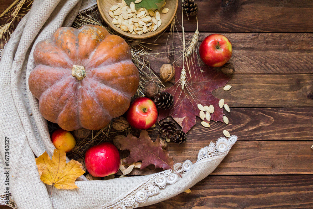 Autumn orange pumpkin, red apples, walnuts, acorns and dry foliage on a wooden background Autumn orange pumpkin, red apples, walnuts, acorns and dry foliage on a wooden background