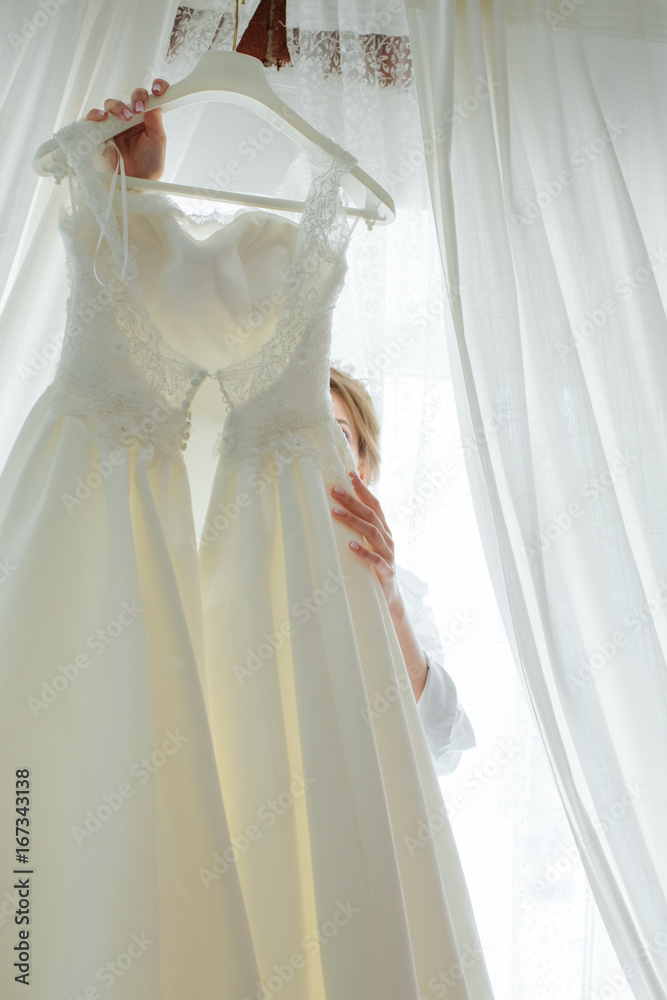 The bride is trying on a wedding dress, looking in front of her The bride is trying on a wedding dress, looking in front of her