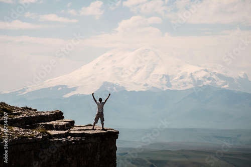 Young man standing on the cliff and enjoying view on the Elbrus