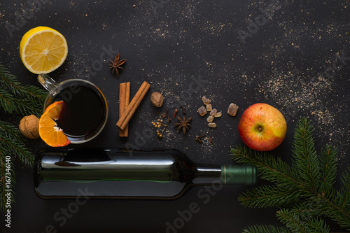 Christmas Mulled wine recipe ingredients on black. Bottle of wine, orange, apple, lemon, cinnamon sticks, anise, nutmeg, cloves and sugar from above. With text space