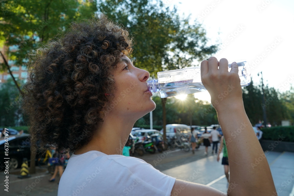 Girl drinking water at the park. Athletic woman Girl drinking water at the park. Athletic woman