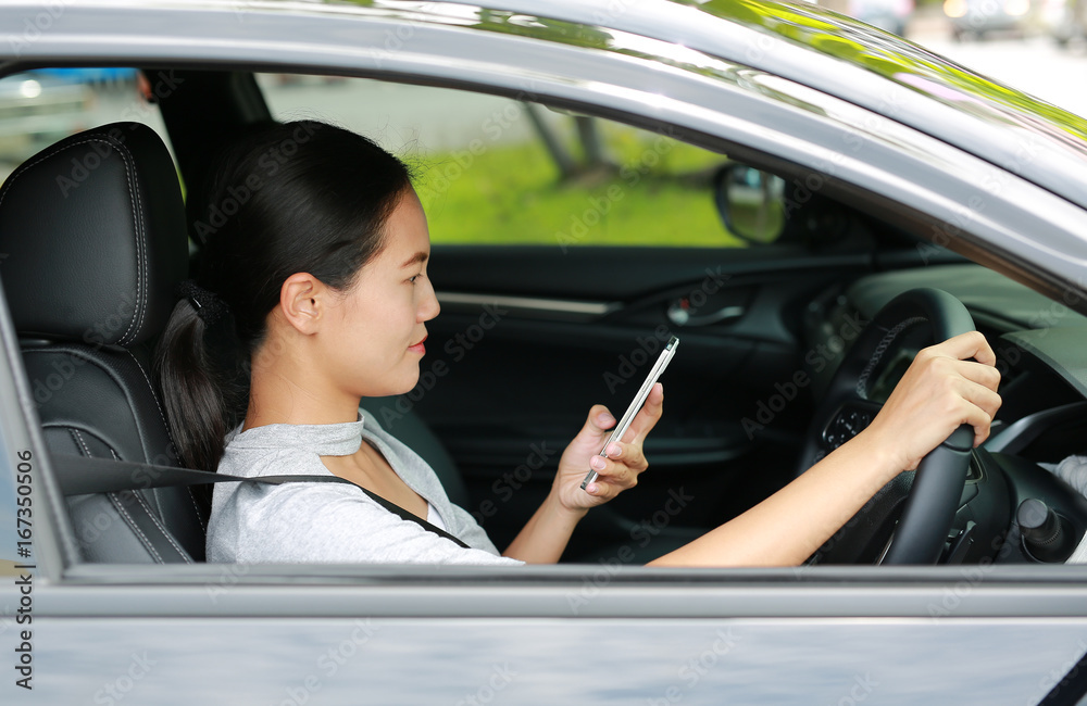 Close-up asian beautiful woman using mobile phone and driving car.