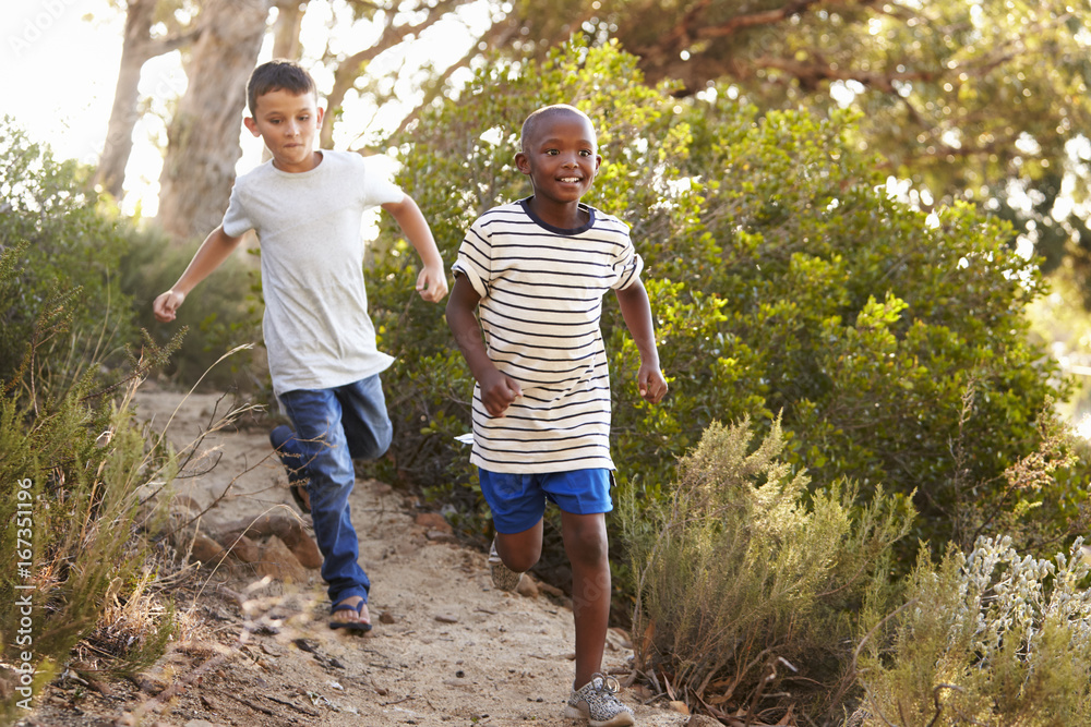 Two happy young boys running down a forest path Two happy young boys running down a forest path