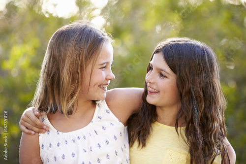 фотографія Portrait of two smiling young girls looking at each other outdoors