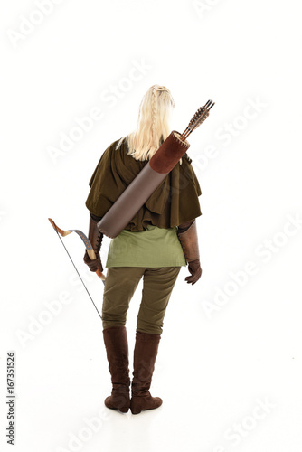 full length portrait of a blonde girl wearing green and brown medieval costume, holding a bow and arrow. isolated on white background. © faestock