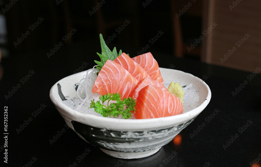 Salmon raw slice or salmon sashimi in Japanese style fresh serve on ice with fresh wasabi on black table. Salmon raw slice or salmon sashimi in Japanese style fresh serve on ice with fresh wasabi on black table.