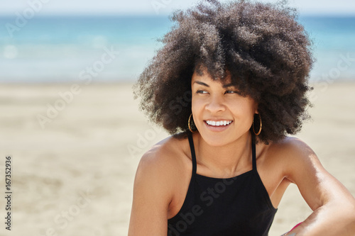 Young pretty afro american woman on beach smiling looking away