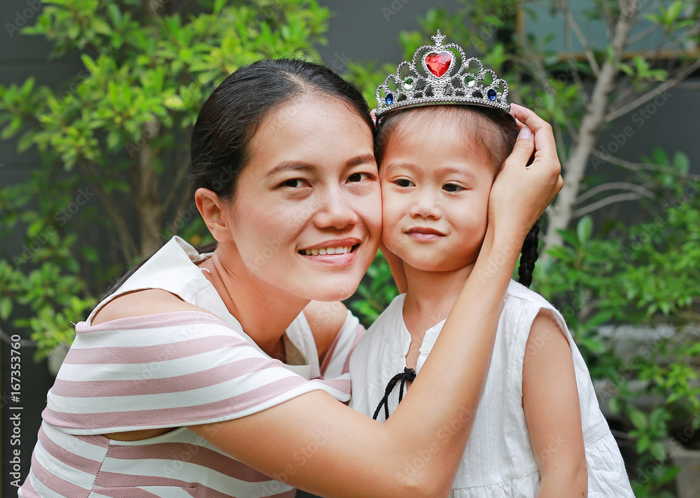 Naklejka premium Mother wearing crown on head of little girl.