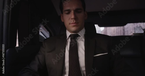 Businessman texts on phone in backseat of car, close up