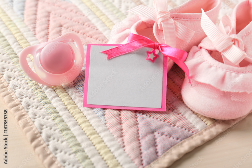 Greeting card with booties and pacifier on table