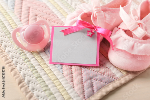 Greeting card with booties and pacifier on table