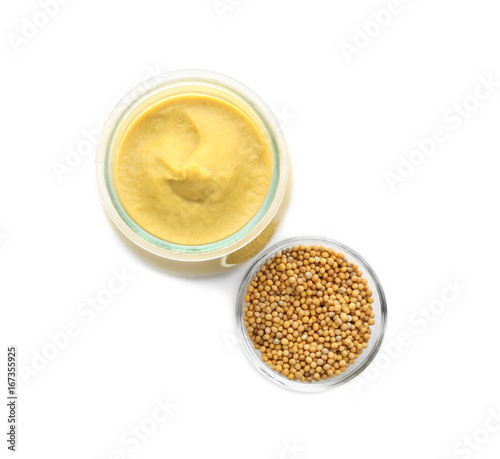 Mustard seeds in bowl and jar with delicious sauce on white background
