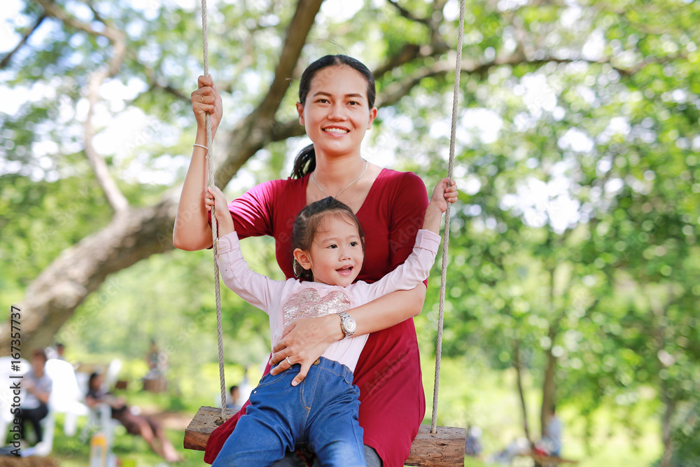 Happy daughter and mother lying on swinging in the garden. Happy daughter and mother lying on swinging in the garden.