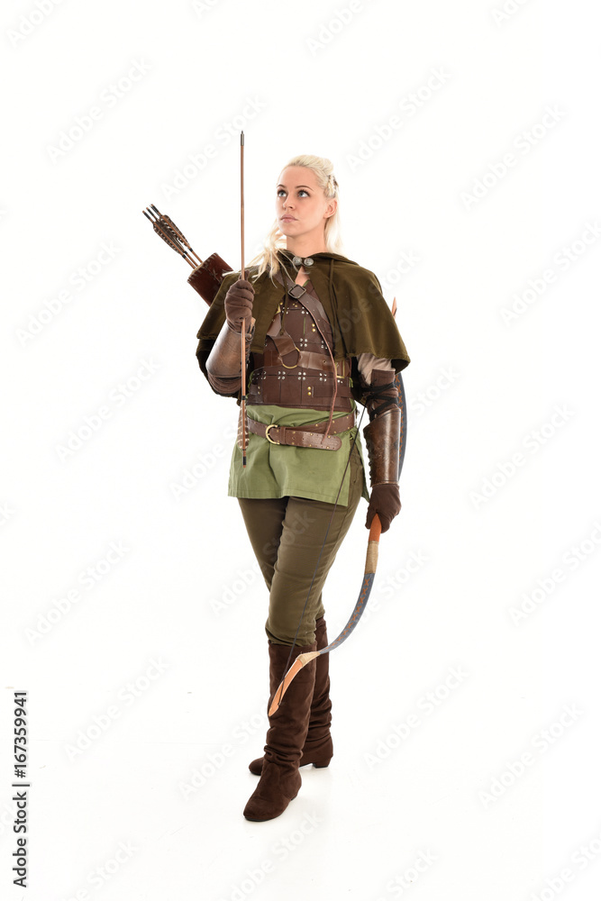 full length portrait of a blonde girl wearing green and brown medieval costume, holding a bow and arrow. isolated on white background. full length portrait of a blonde girl wearing green and brown medieval costume, holding a bow and arrow. isolated on white background.