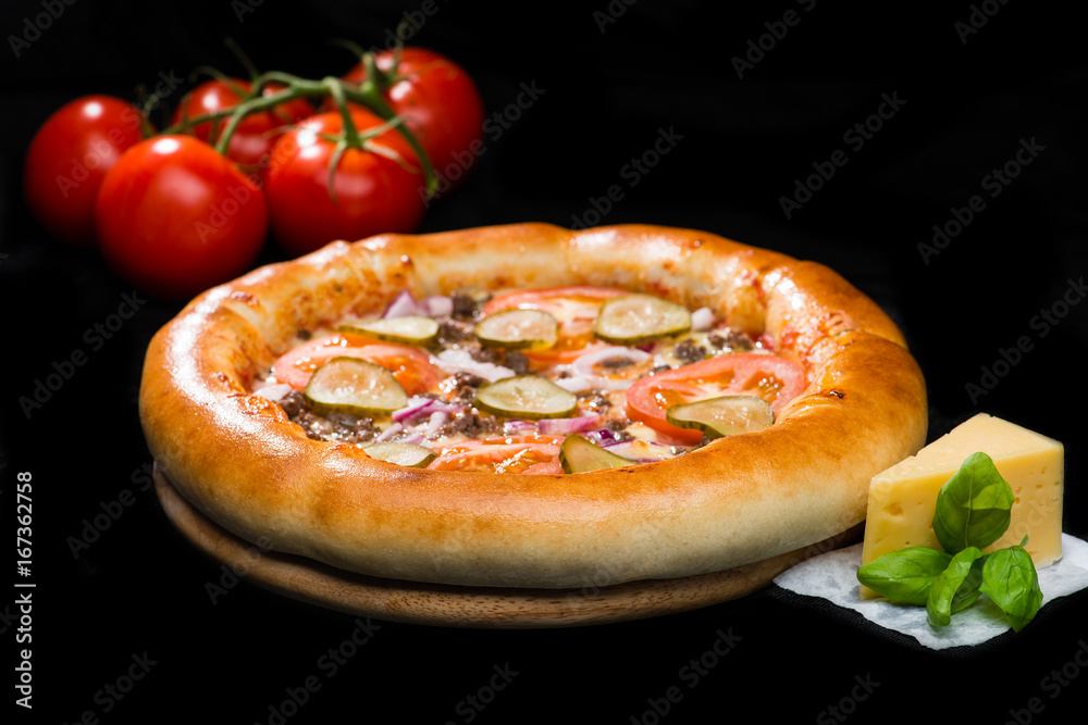 selective focus on appetizing Italian pizza with meat, cheese, sliced tomatoes, onion and pickled cucumbers on round wooden board on dark background, near tomatoes and cheese selective focus on appetizing Italian pizza with meat, cheese, sliced tomatoes, onion and pickled cucumbers on round wooden board on dark background, near tomatoes and cheese