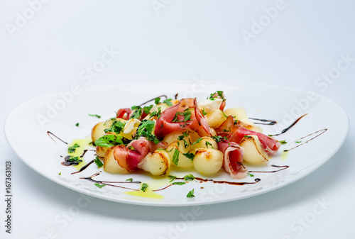 classic Italian summer delicious fresh salad with cheese, parma ham and soy sauce on white plate, on light background photo