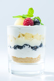 sweet Italian Tiramisu dessert in a glass with raspberries, blueberries, mint and mascarpone on light background
