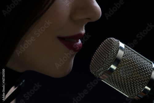 Singer in front of a microphone. Isolated on a dark background