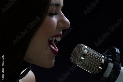 Singer in front of a microphone. Isolated on a dark background