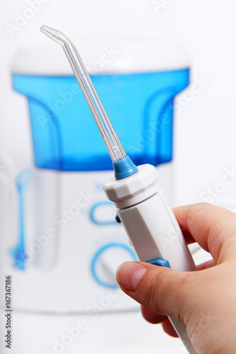 man's hand holds the handle of oral irrigator with an individual toothbrush. Side nozzles for tongue, delicate cleansing sensitive gums. Dentists recommend taking care of teeth cavity irrigator