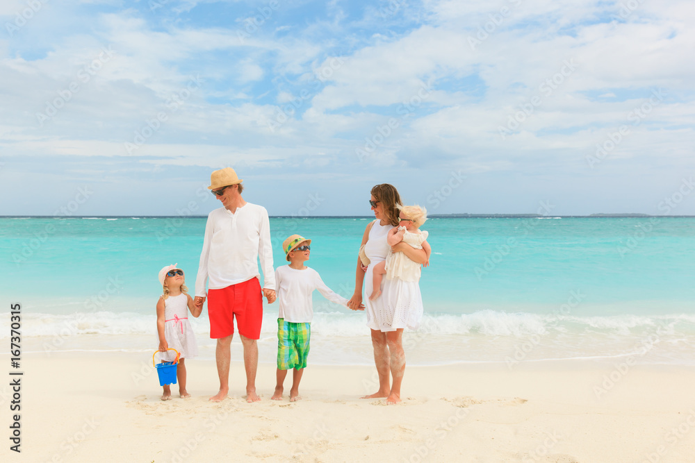 happy family with three kids walk on beach