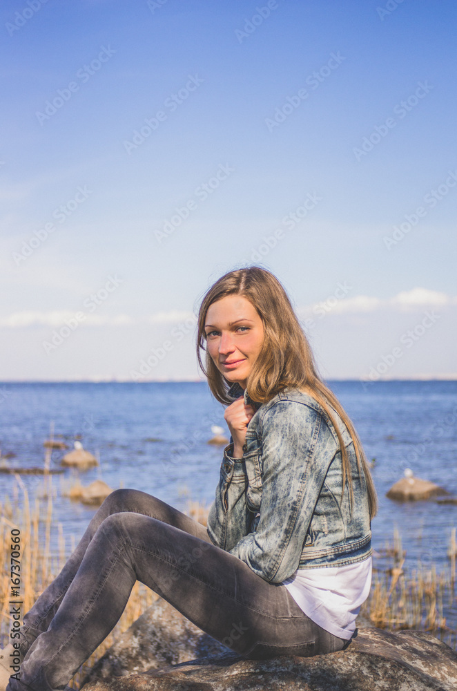 Frozen woman sitting on a stone on the background of the sea