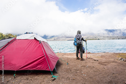Woman backpacker with her camping tent near lake.